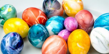 Πασχαλινά αυγά βαμμένα με την τεχνική της κλωστής πάνω σε ξύλινο τραπέζι